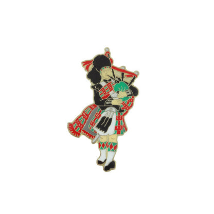 A hat pin featuring an illustration of a female and male figure in traditional Scottish attire, with the female holding a baby and the male holding a bagpipe.