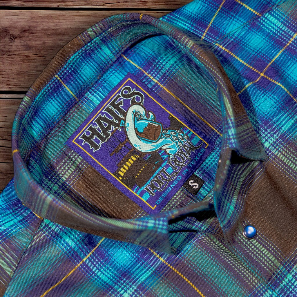 Blue plaid shirt with a logo patch on a wooden surface